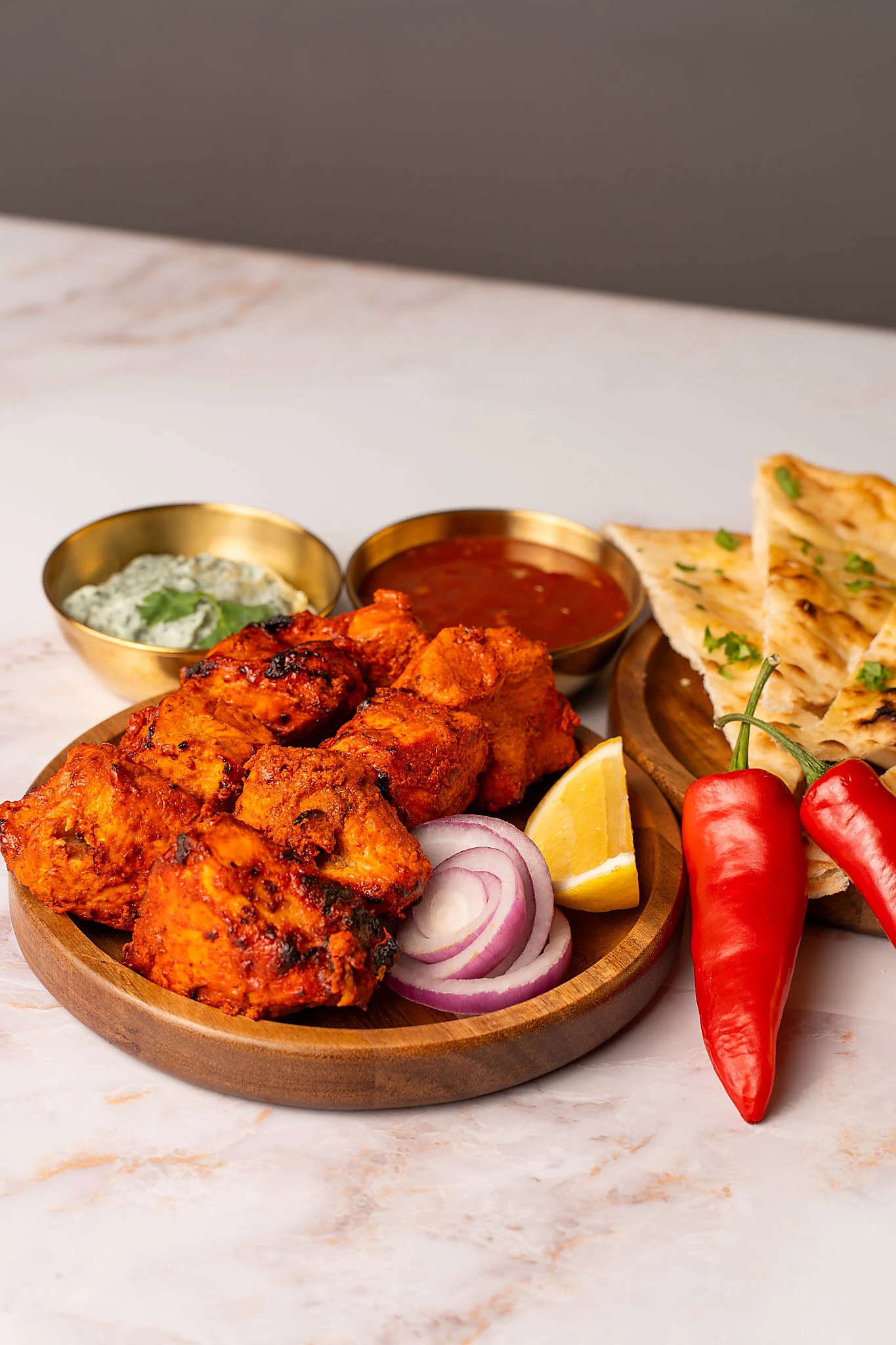 Spiced chicken tikka alongside naan and dips